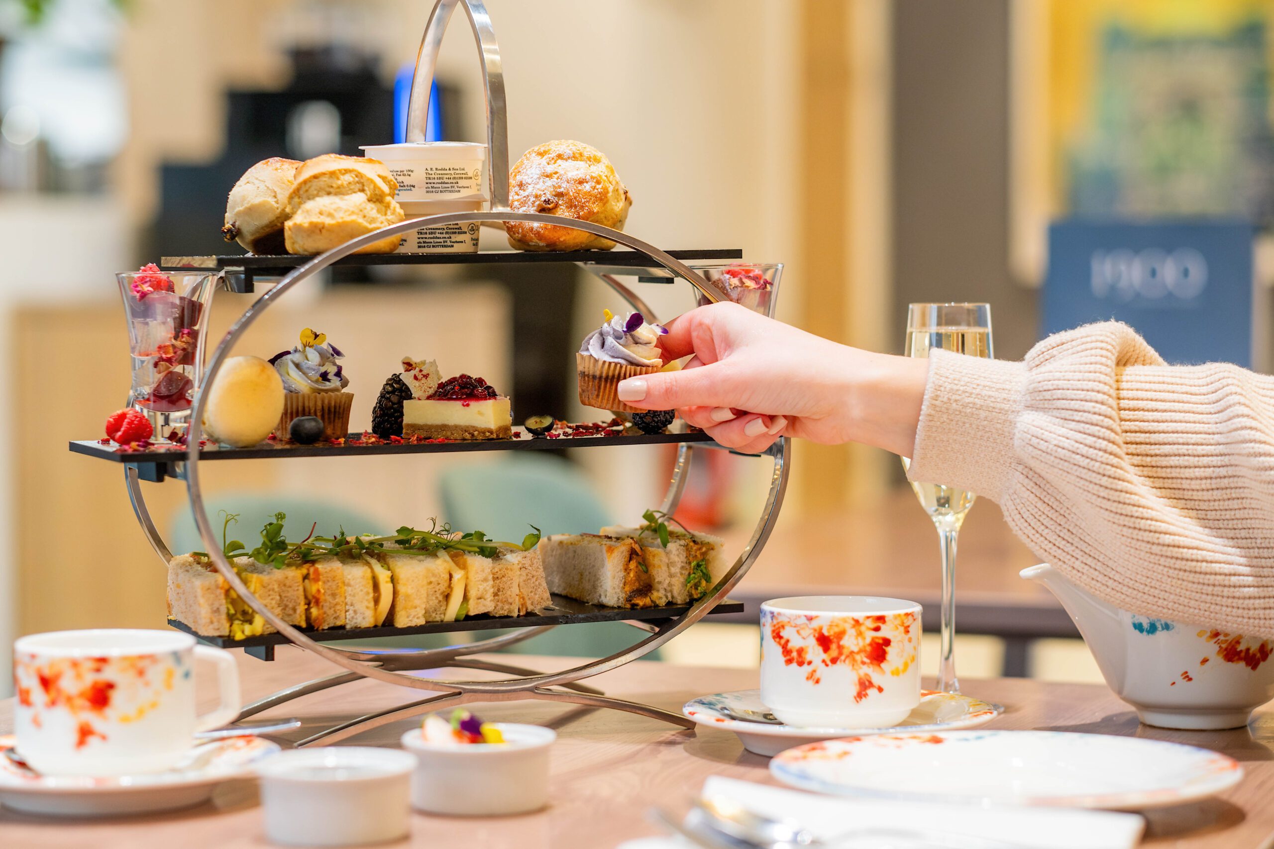 A person picking a cupcake off an afternoon tea stand