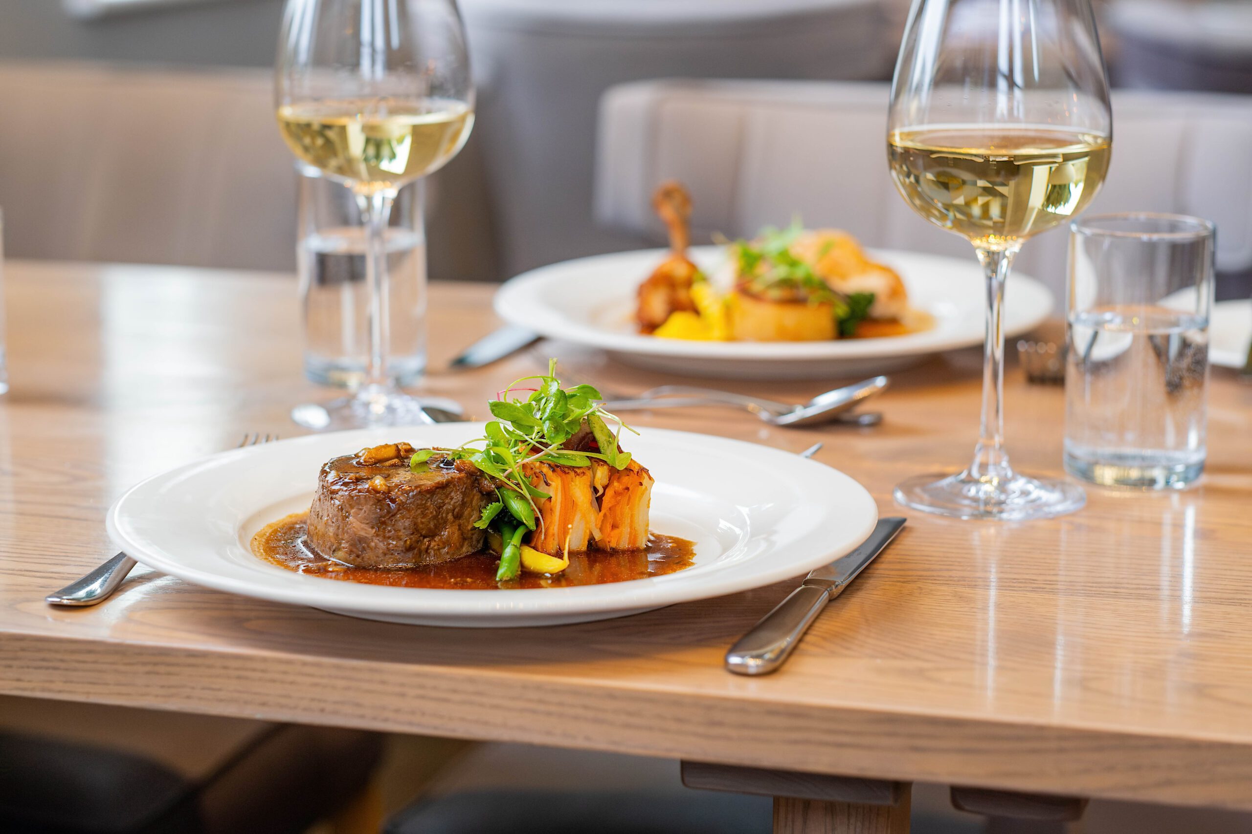 Two dishes off the restaurant menu with two glasses of white wine