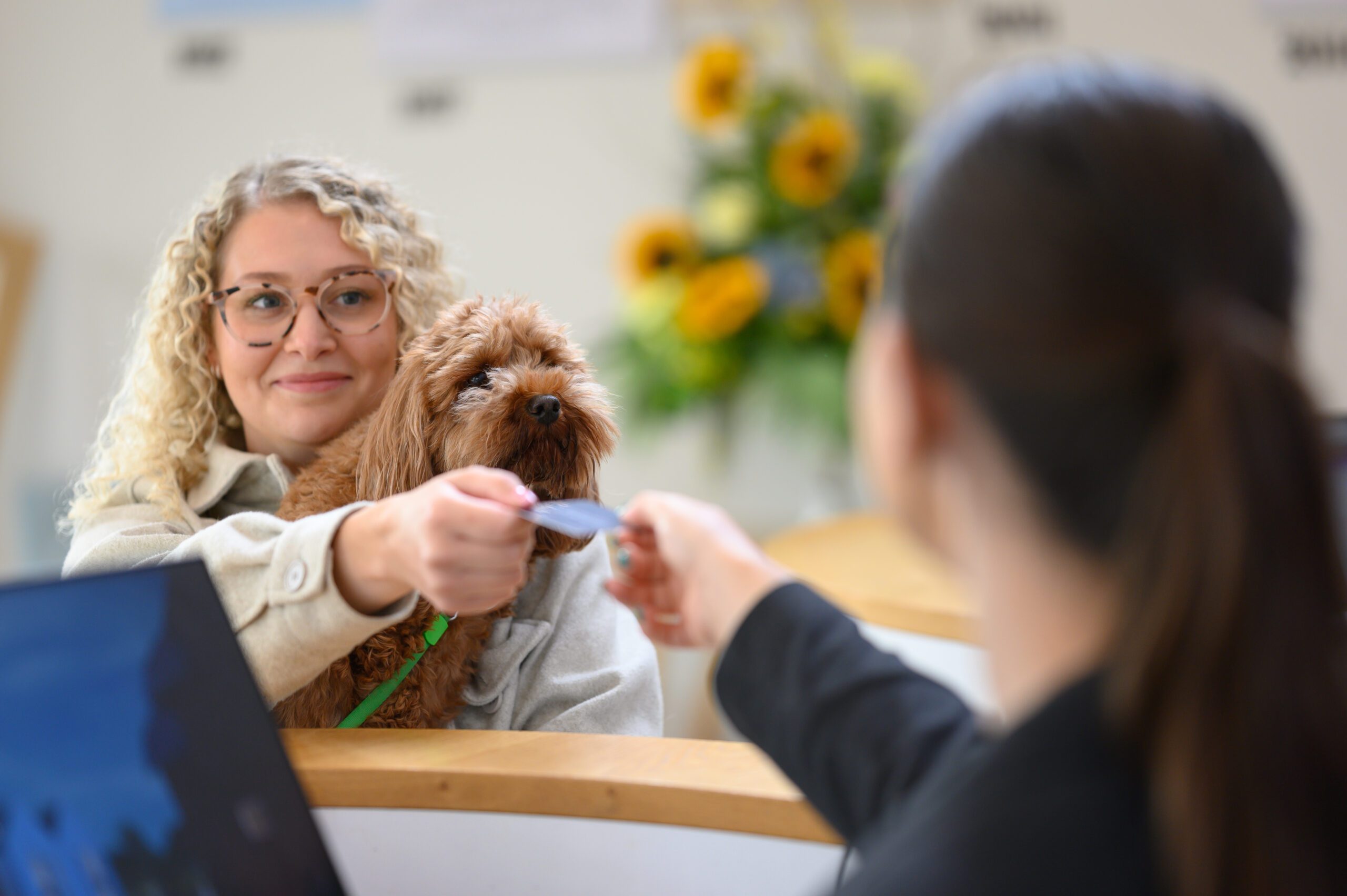 A guest holding her dog receiving her room card