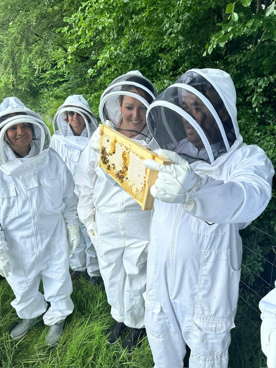 EPH team dressed in beekeeper uniform holding up a hive