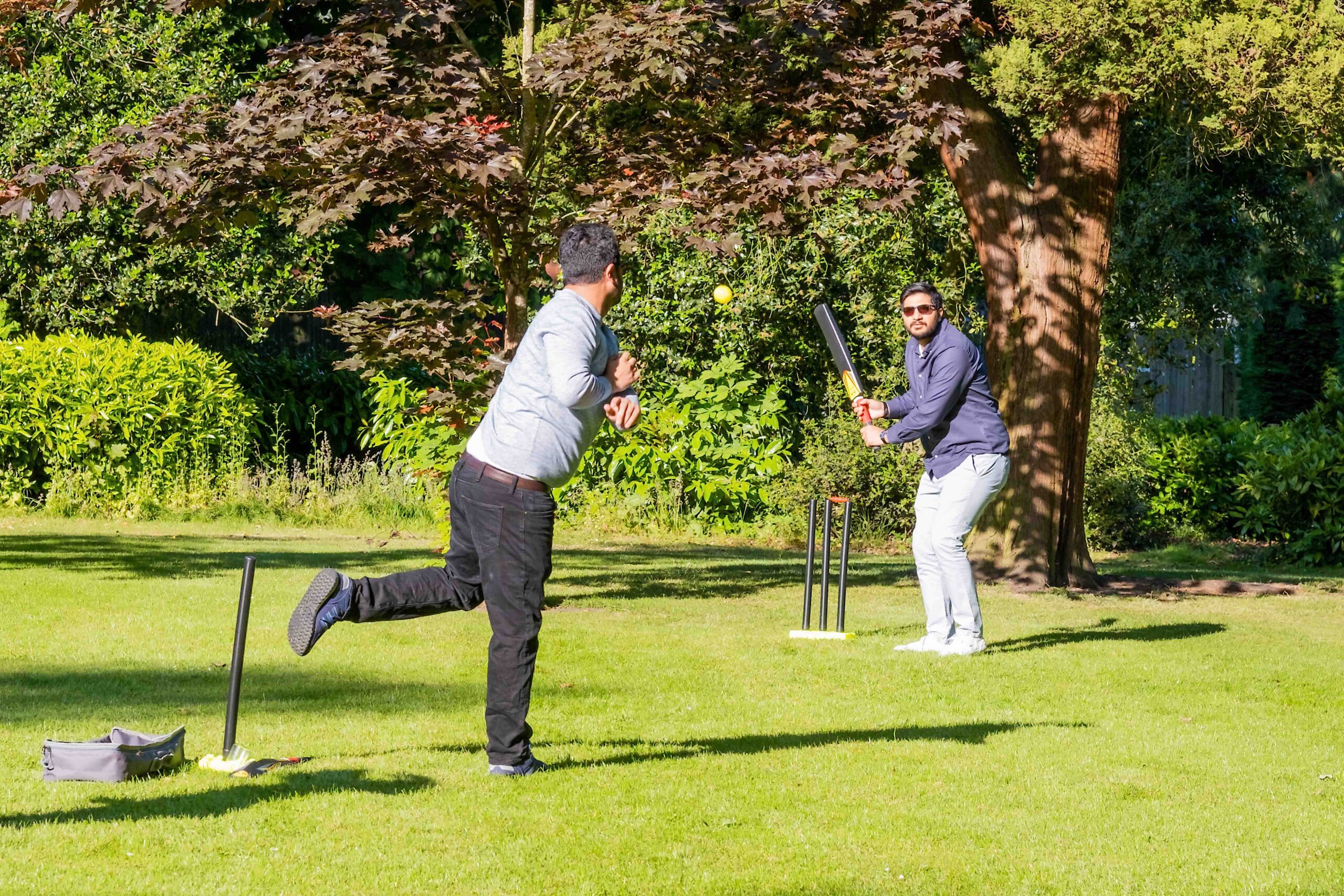 Two people playing cricket outside