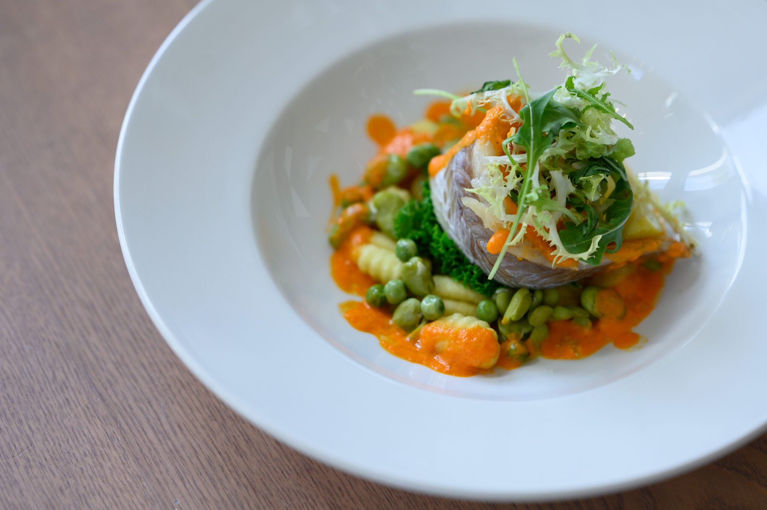 A dish of gnocchi with salad and vegetables