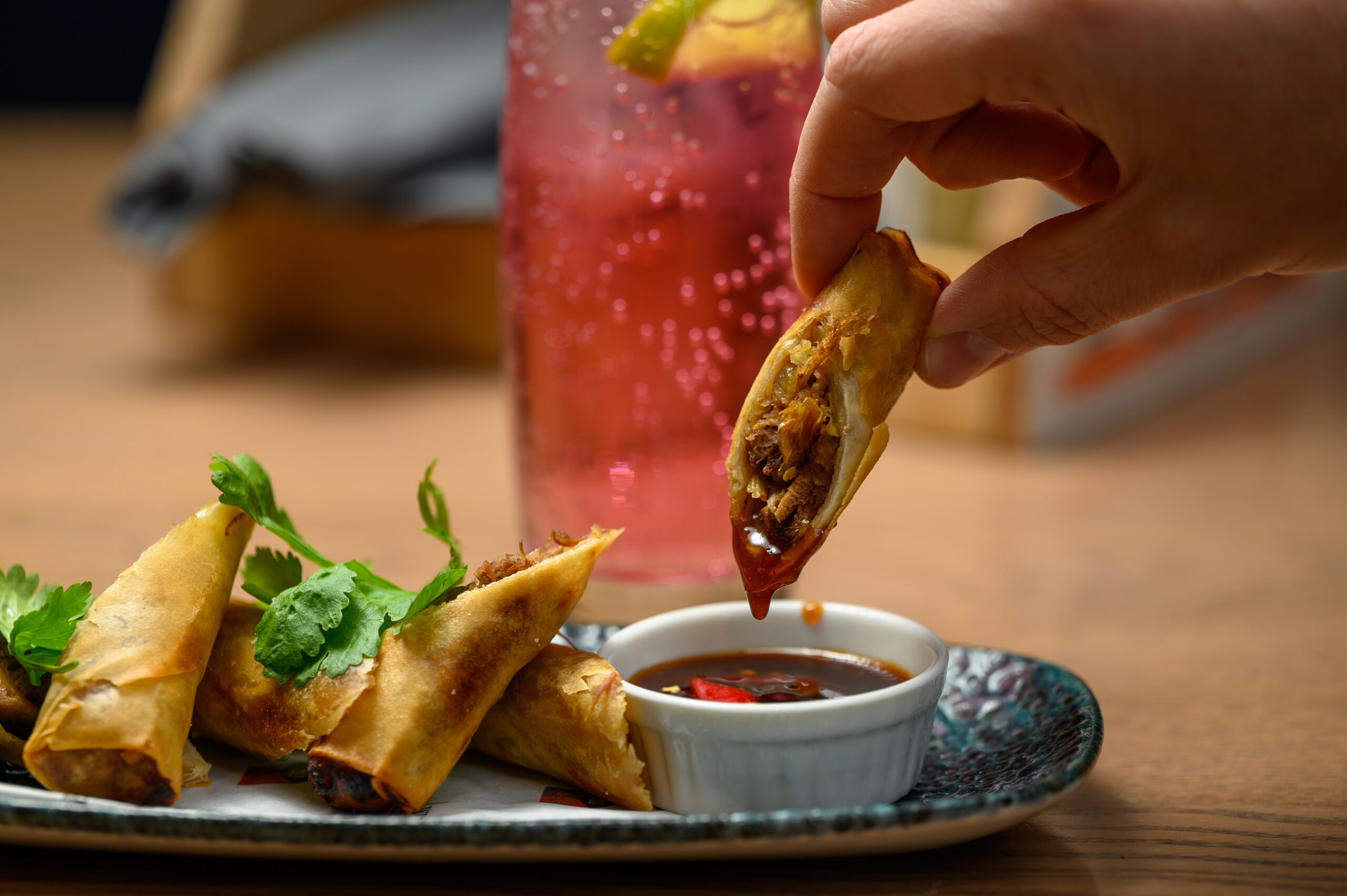 Someone dipping a spring roll into sauce