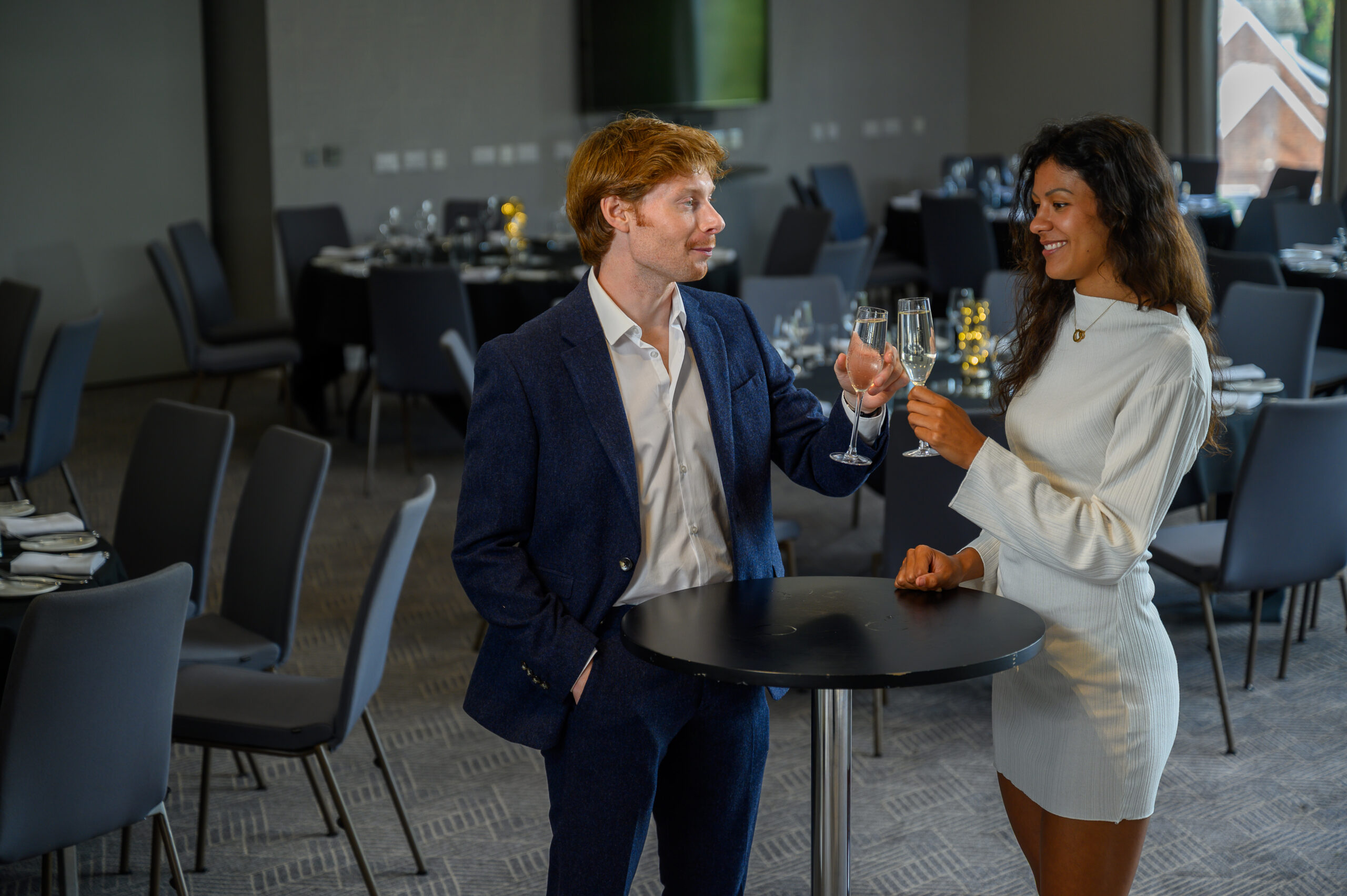 Two people stood at poser table with glasses of fizz